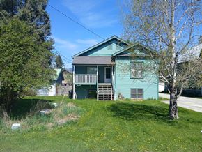 Whitefish apartment for rent - A blue house with a green roof and a tree in front.